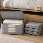 Grey collapsible bedding storage bag open with folded blankets and three bags stored flat