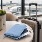 Sky blue passport holder wallet beside carry-on luggage at an airport